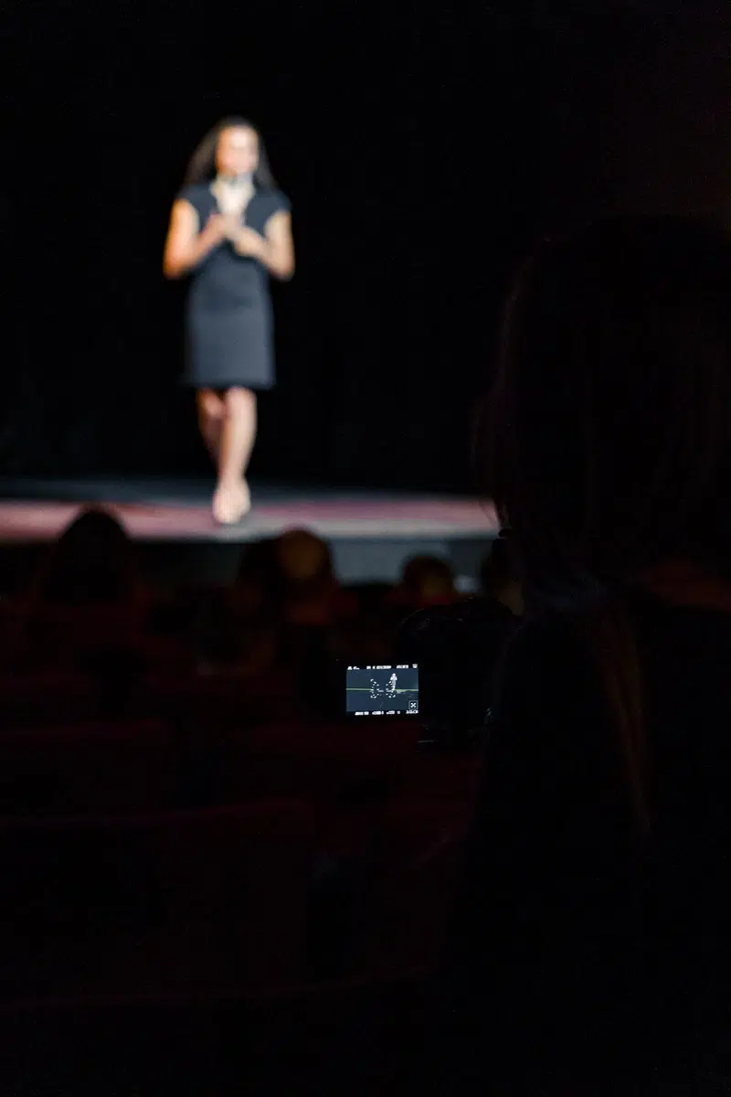 femme prise de parole en public sur scène et face caméra
